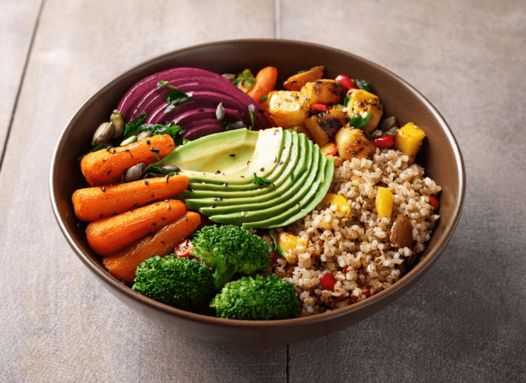 A bowl bursting with roasted veggies, grains, and avocado